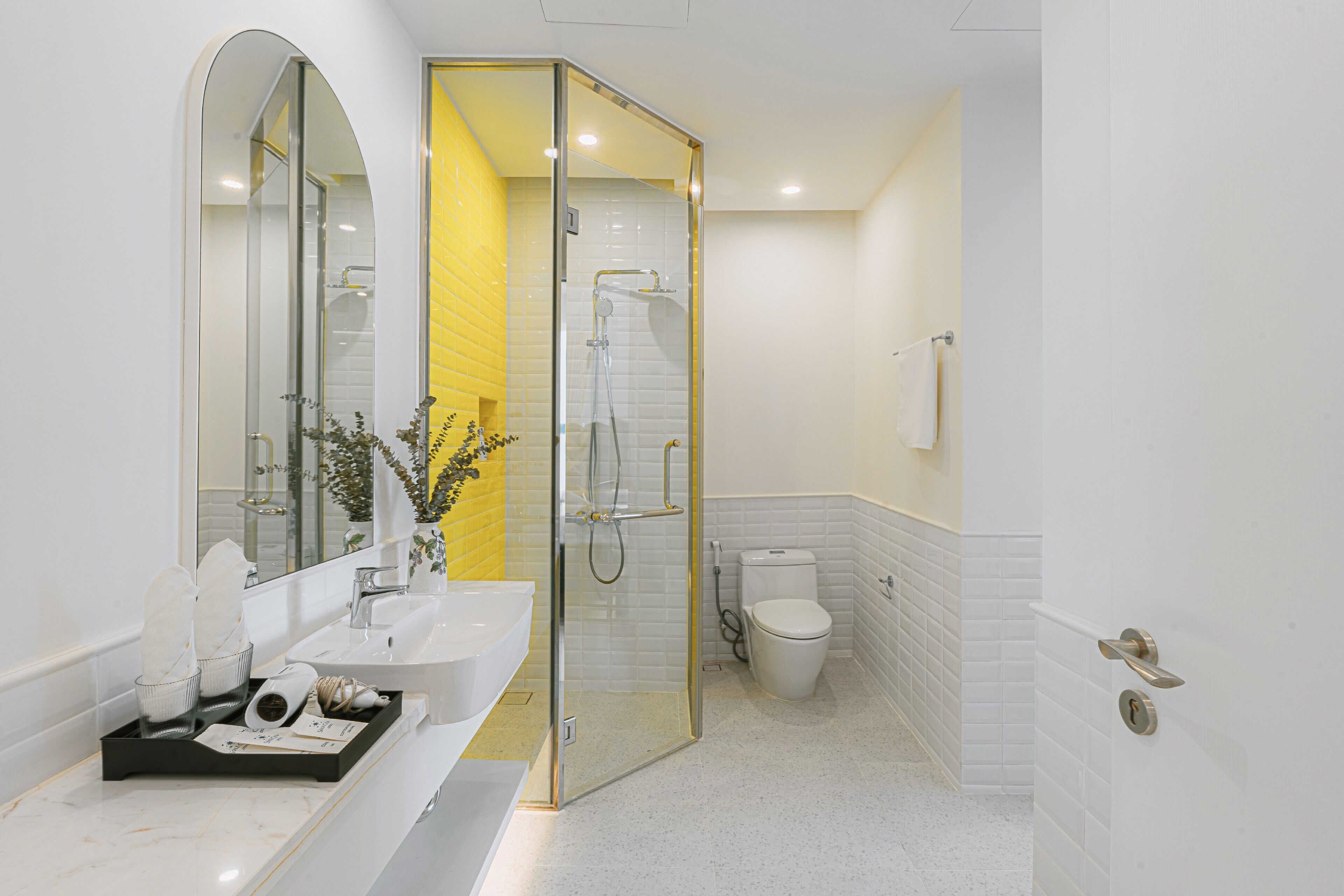 Un baño moderno con ducha de mampara de vidrio, lavamanos blanco y retrete.