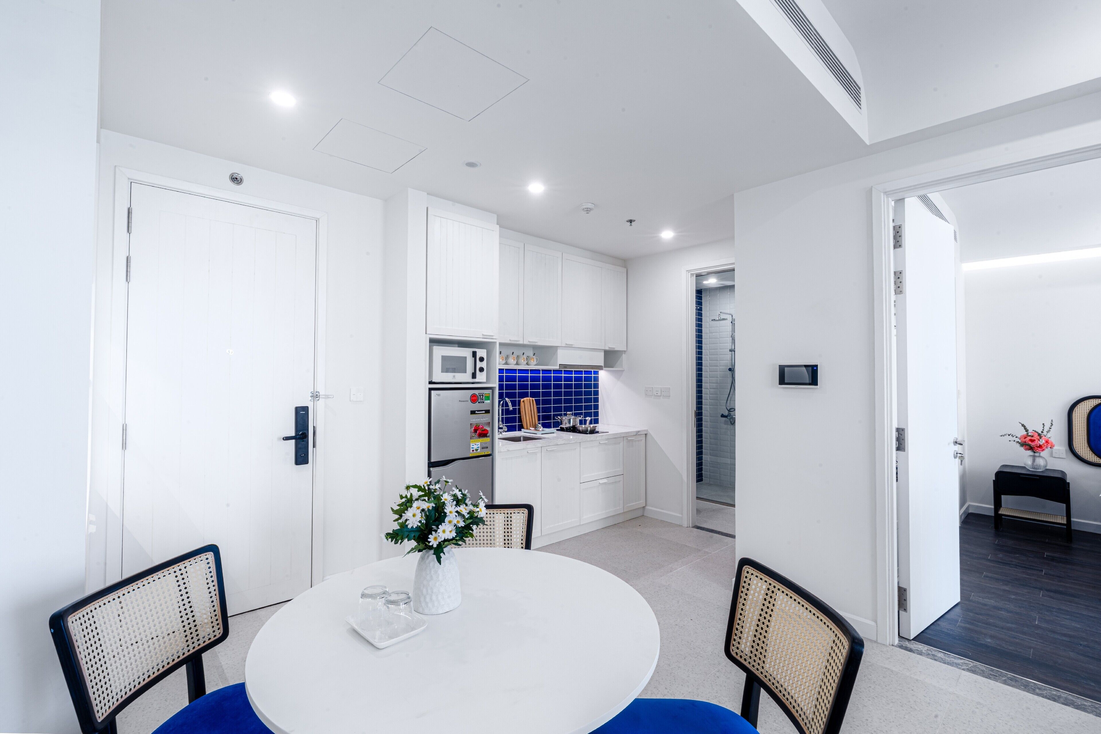 A modern kitchen with white cabinets, a blue backsplash, and a dining area with a round table and chairs.