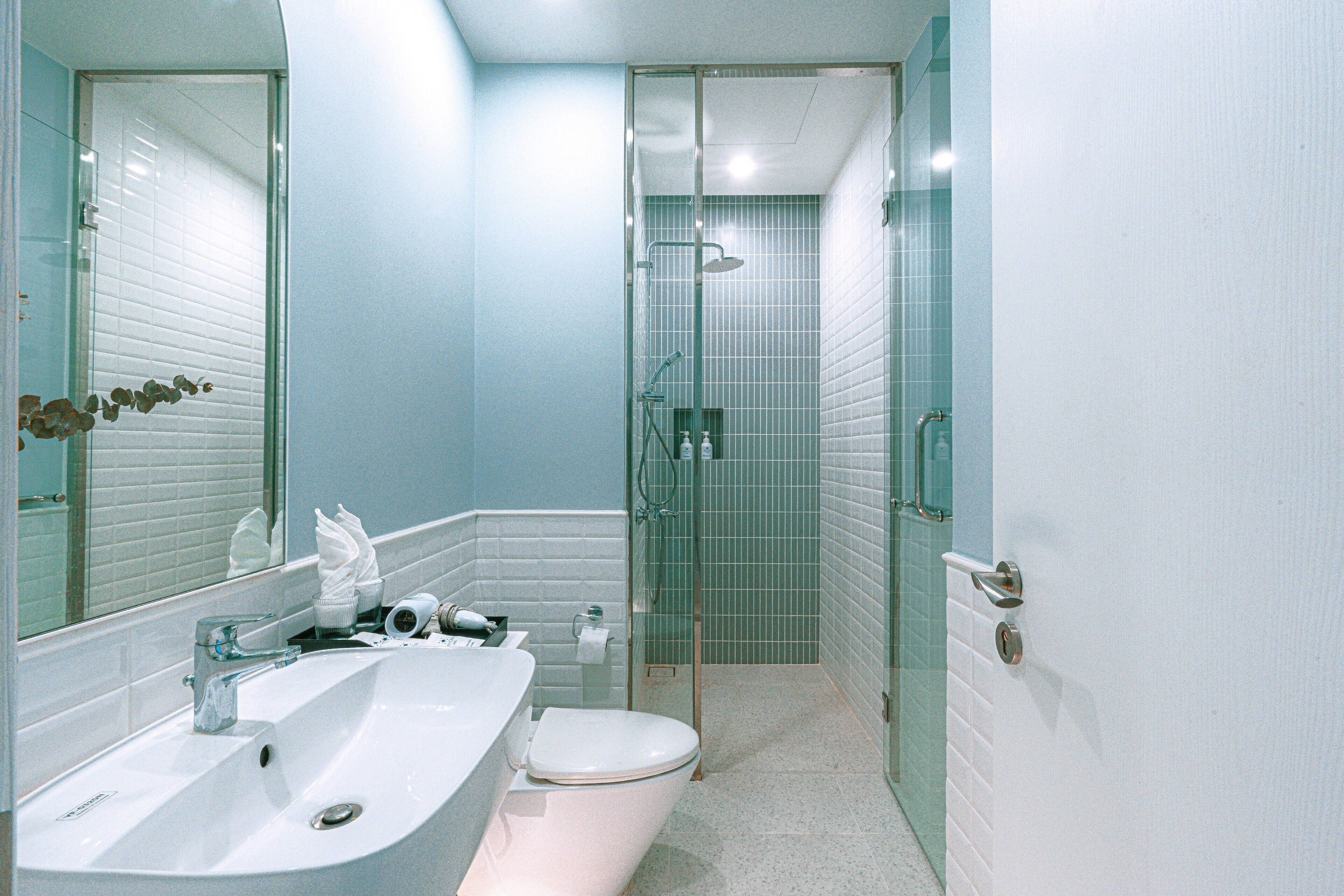 Un baño con lavamanos blanco, inodoro y cabina de ducha de vidrio.