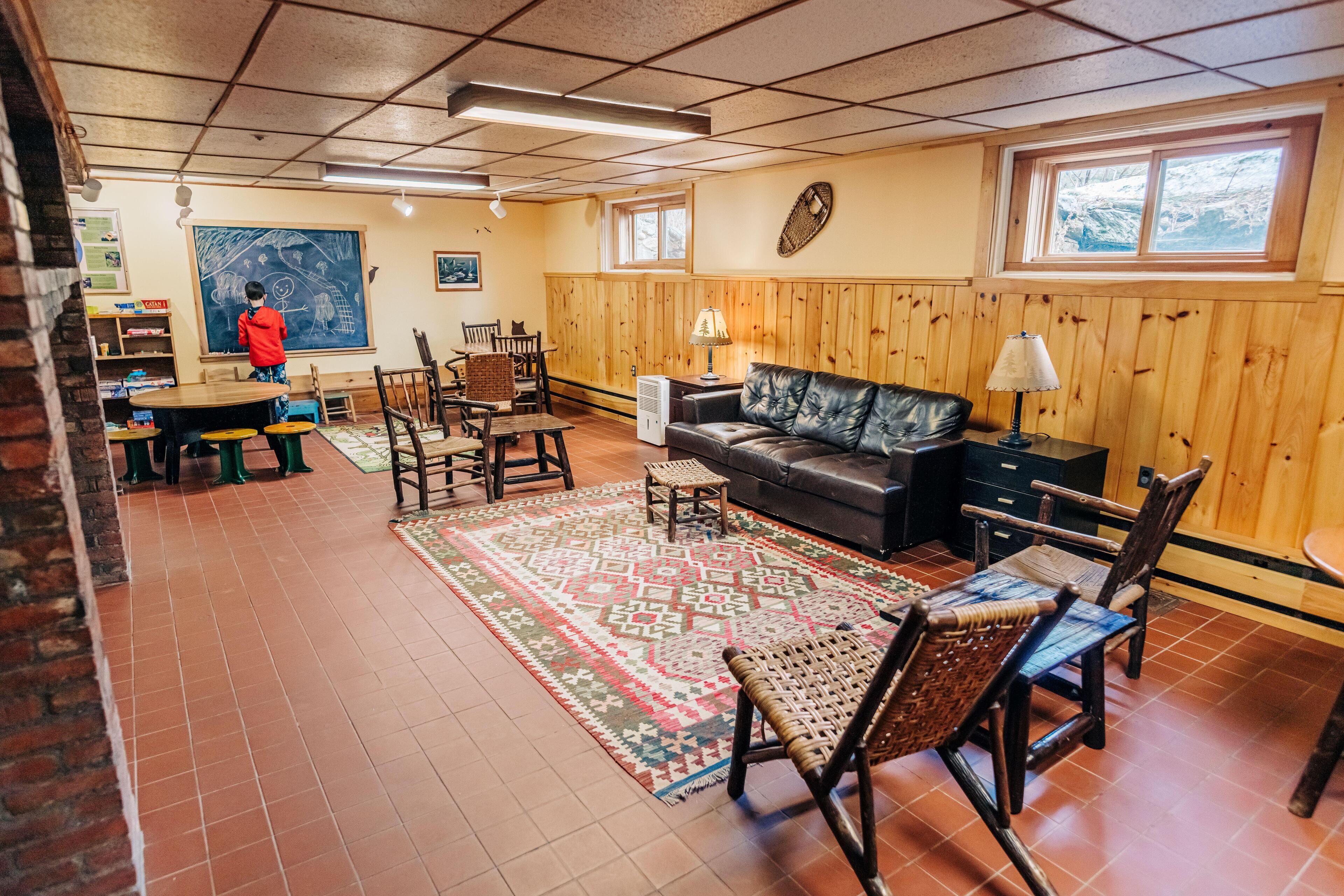 A cozy living room with a fireplace, a large rug, and a couch. There is a dining area with a table and chairs.