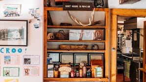Un intérieur chaleureux avec une étagère en bois où sont exposés divers objets, un panneau indiquant les heures de silence, et des certificats encadrés accrochés au mur.