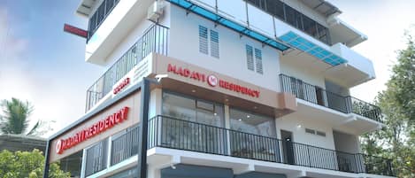 A multi-story building with a sign indicating 'Maday Residence' and 'Rooms'.