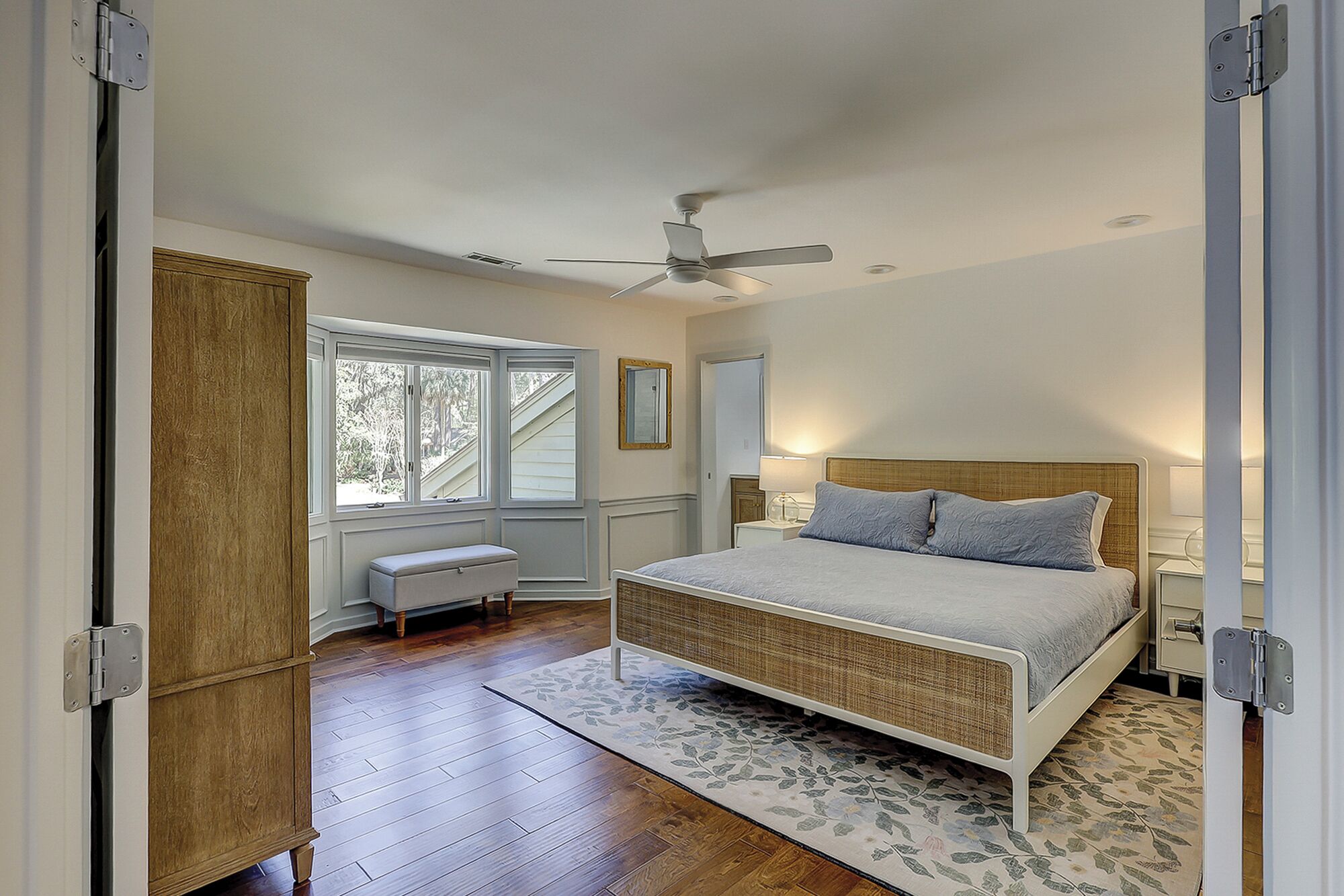 Une chambre à coucher avec un lit, un ventilateur de plafond, une fenêtre et une porte.