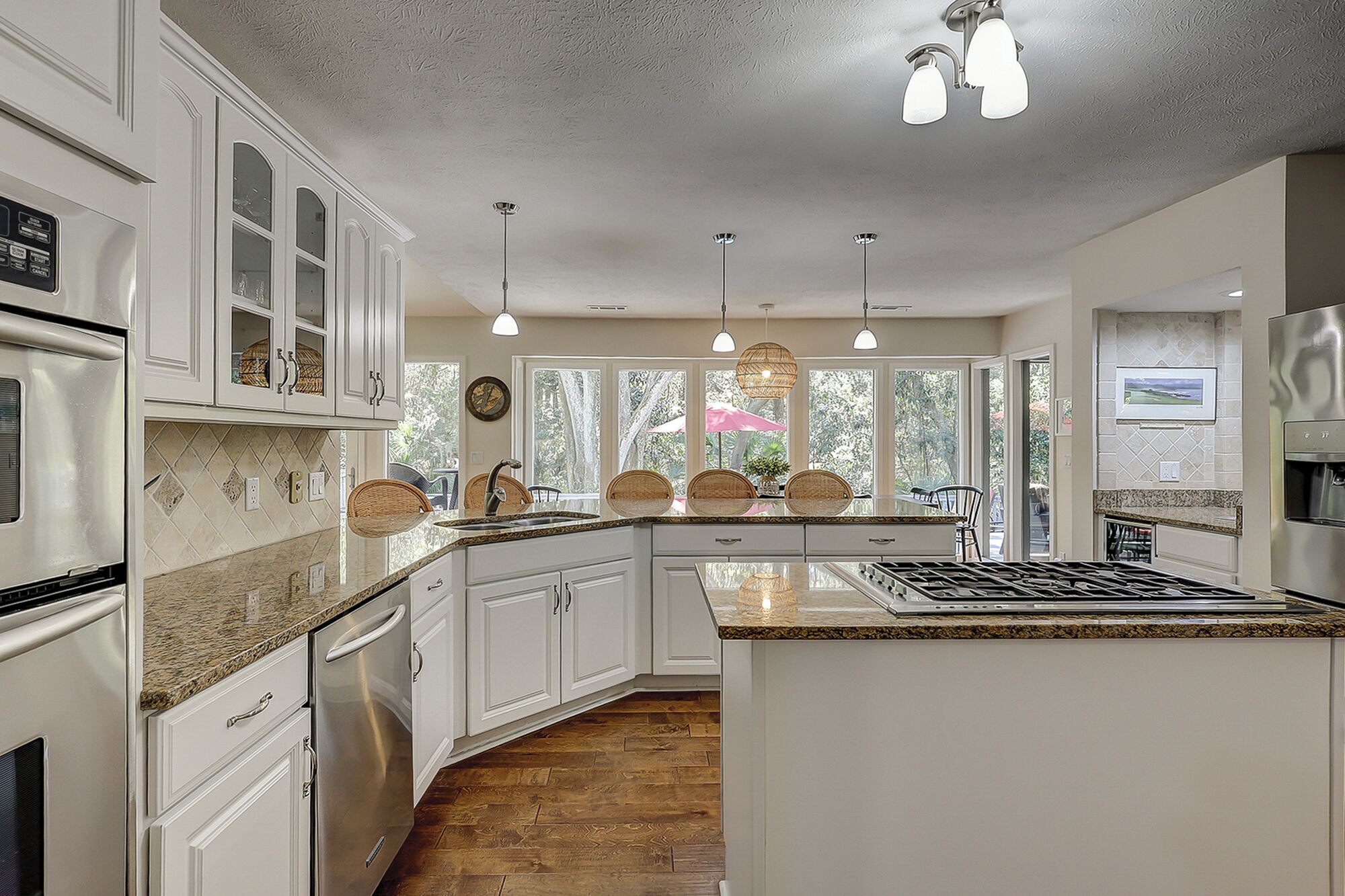 A spacious kitchen with white cabinets, granite countertops, and stainless steel appliances.