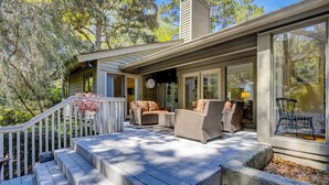 A covered outdoor deck with steps leading up to a seating area with wicker furniture.