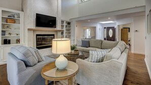 A living room with a fireplace, sofas, a television, and a lamp.