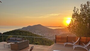 A hot tub on a wooden deck with a view of a sunset and mountains. - 180° Sea View Villa **** Truly Unique View - Hillside on the Seafront (Carqueiranne)