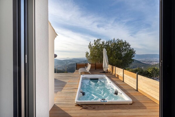 A hot tub on a wooden deck with a view of a tree and distant hills. - 180° Sea View Villa **** Truly Unique View - Hillside on the Seafront (Carqueiranne)