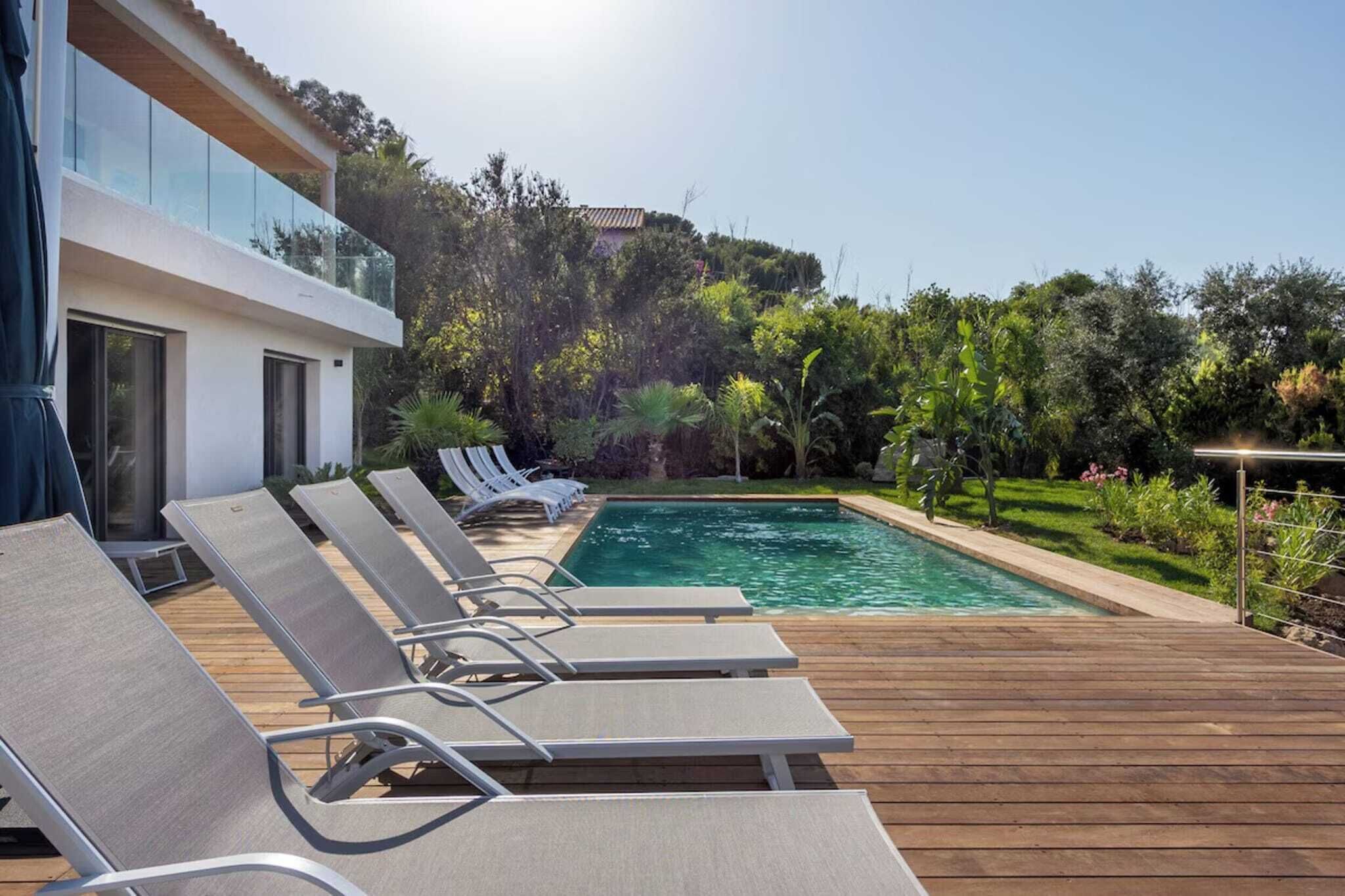 Ein moderner Poolbereich im Freien mit Liegestühlen und einer Holzterrasse.