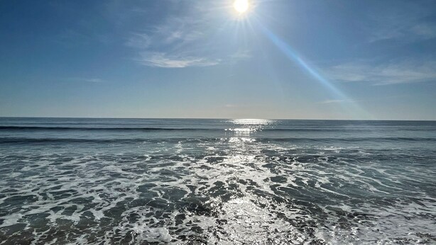 Ein Strand mit glitzerndem Wasser im Sonnenlicht.