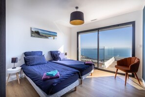 A bedroom with two beds, a large window with a view, a chair, and a lamp. - Villa Sea View La Californie–Hillside on the Seafront–View of the Golden Islands (Carqueiranne)