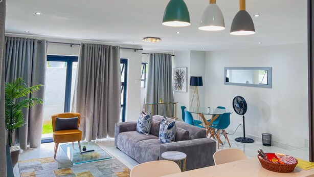 Un salon moderne avec un canapé, une table basse et un coin repas comprenant une table et des chaises en verre.