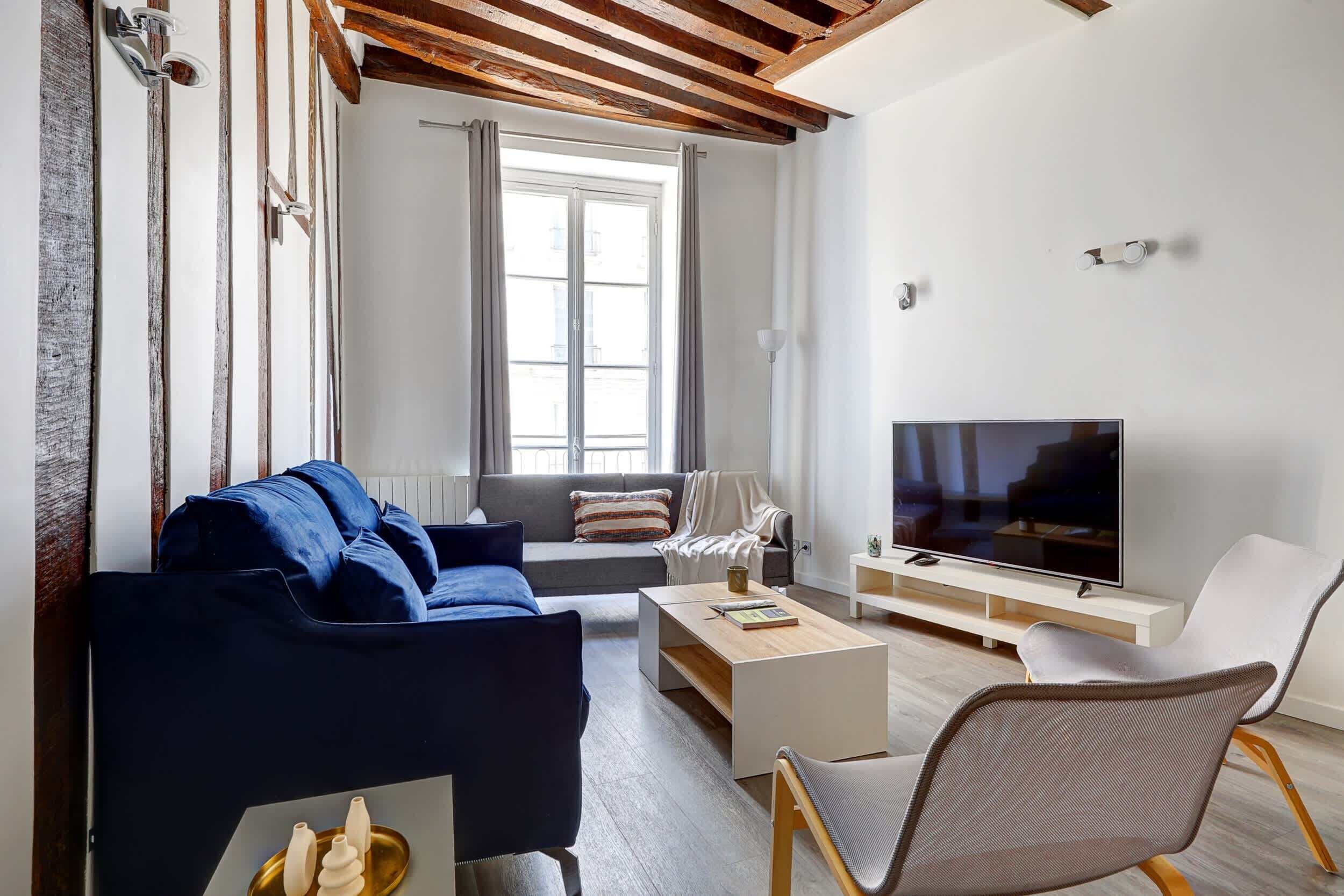 A modern living room with a sofa, coffee table, TV, and seating area.