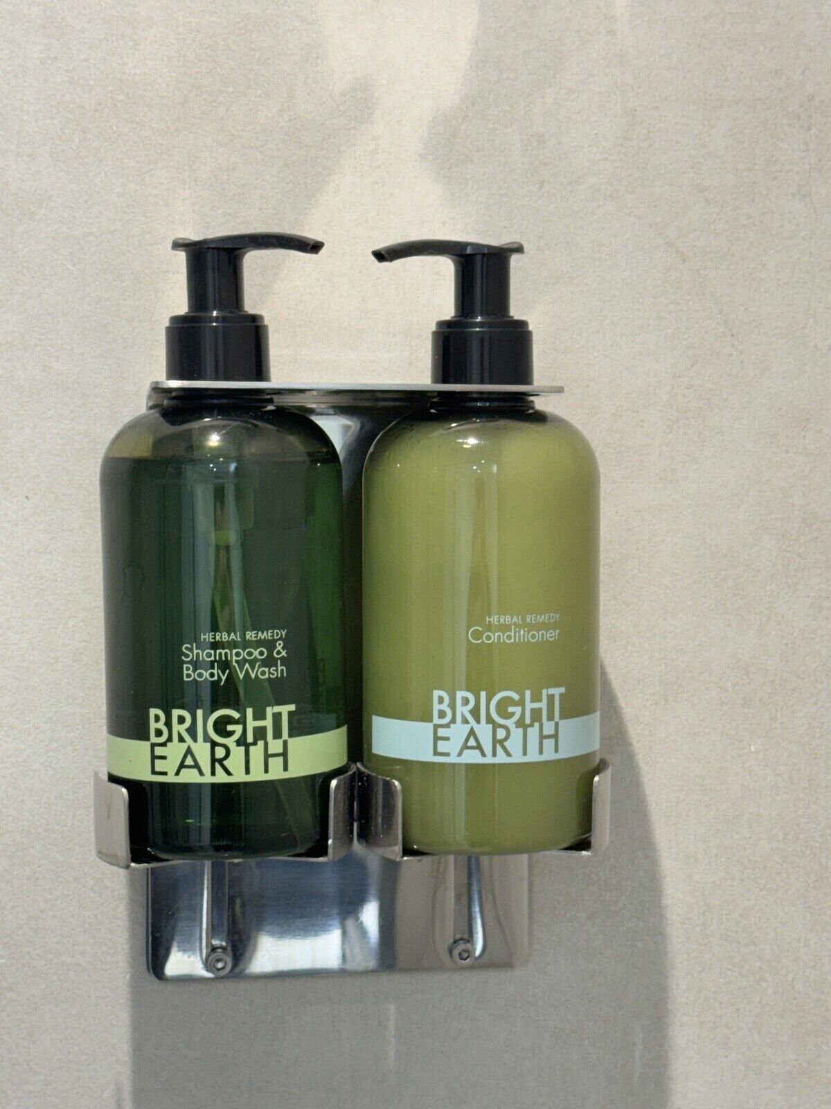 Duas embalagens de shampoo e condicionador Bright Earth fixadas numa parede.