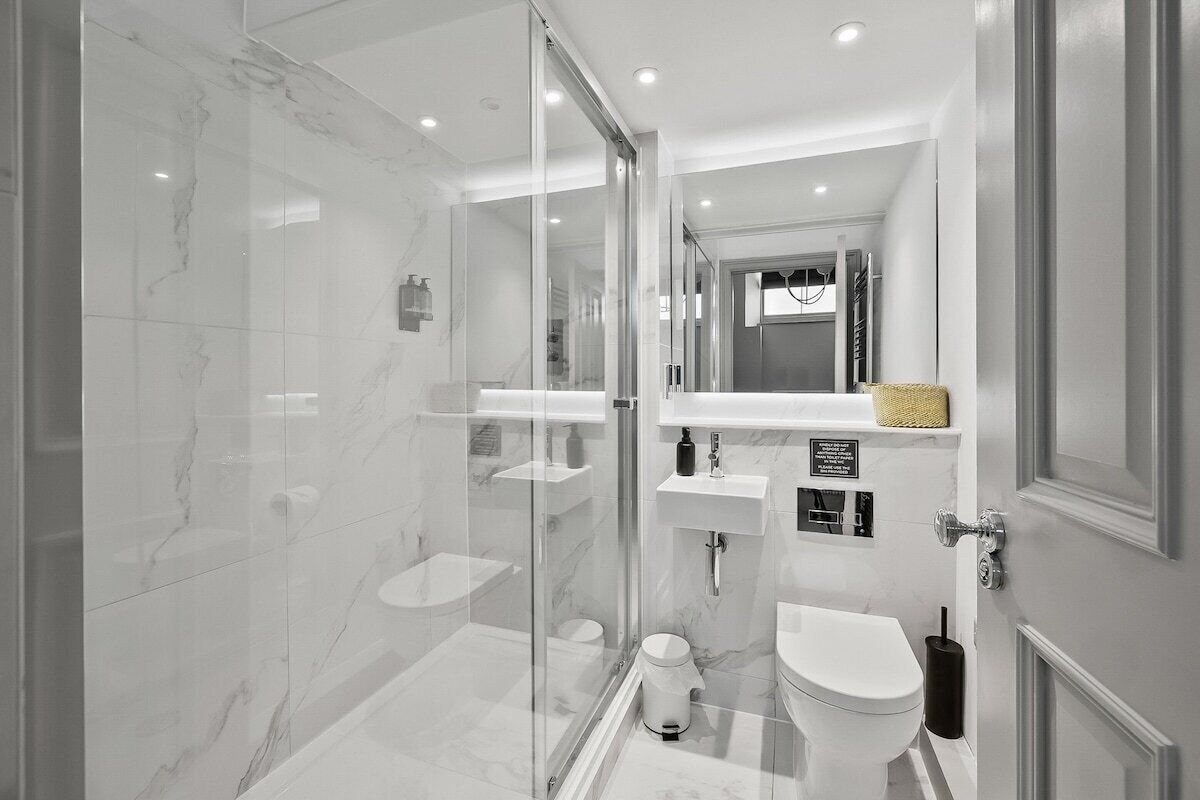 Une salle de bain moderne avec une douche à parois de verre, des toilettes blanches et un lavabo.