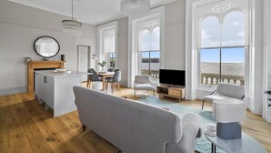 Ein geräumiges Wohnzimmer mit großem Fenster, Essbereich und Küche.