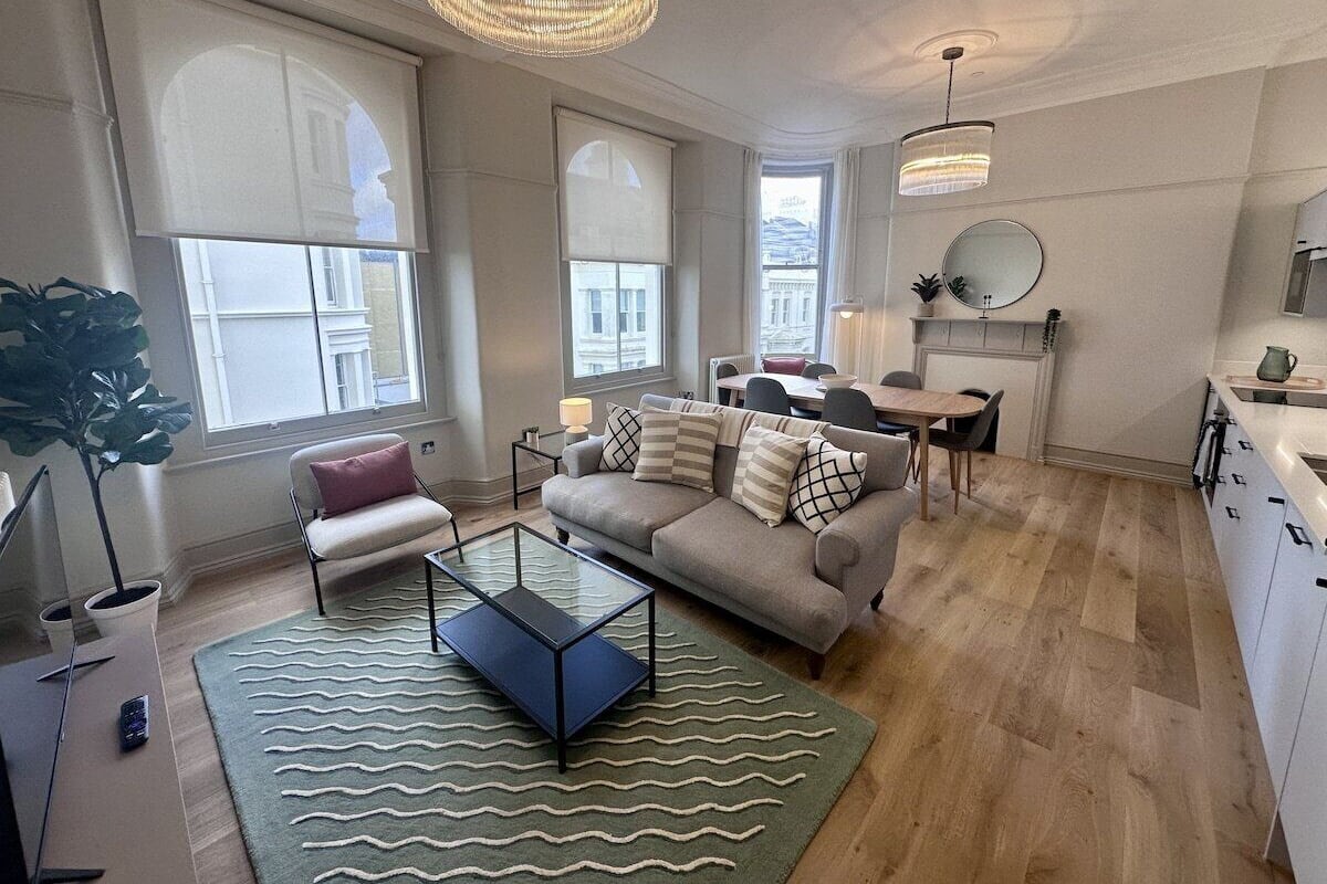 A modern living room with a sofa, coffee table, and a dining area with a table and chairs.