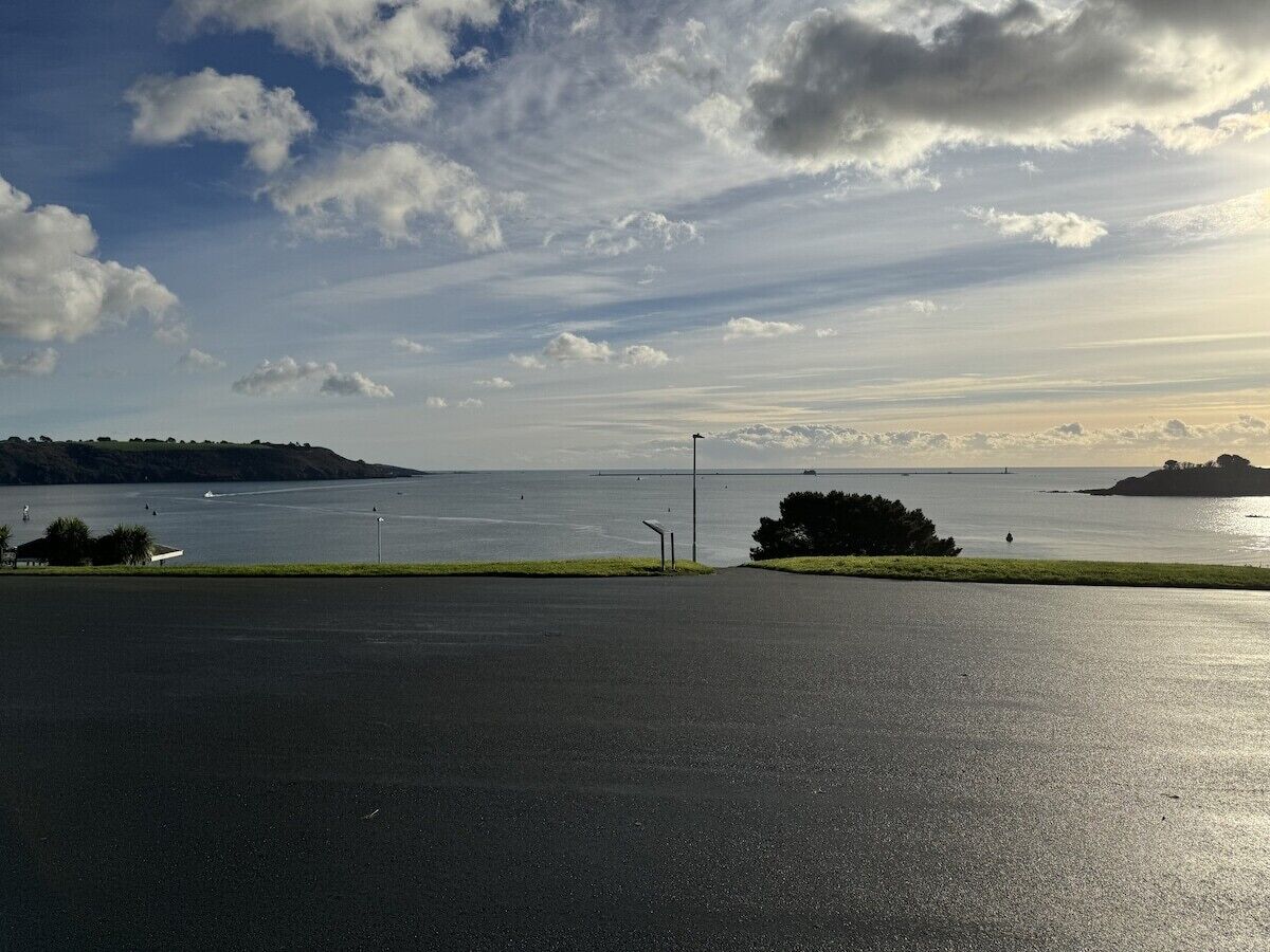 Ein Parkplatz mit Blick auf ruhiges Gewässer, eine entfernte Insel und einen klaren Himmel.