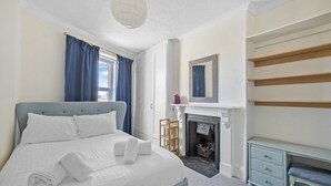 A bedroom with a bed, a fireplace, a mirror, and a dresser. - Admiralty Retreat by Pureserviced (Plymouth)