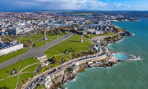 An aerial view of a coastal city with a prominent lighthouse, a marina, and a large public square. - Admiralty Retreat by Pureserviced (Plymouth)