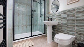 A modern bathroom with a glass-enclosed shower, a pedestal sink, and a toilet. - Luxury Ground Floor 2 bed Apartment (Plymouth)
