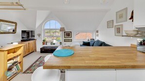 Un'ampia cucina con isola in legno, mobili bianchi e una grande finestra che offre vista all'esterno.