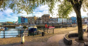 A waterfront promenade with boats docked, a brick pathway, and colorful buildings in the background. - Bantham Mews by Pureserviced 1 Bedroom Luxury Mews (Plymouth)