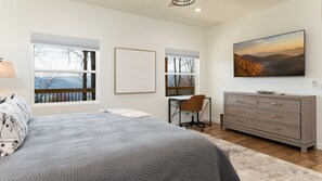 Ein Schlafzimmer mit Bett, Schreibtisch, Stuhl, Kommode und einem Bild an der Wand.