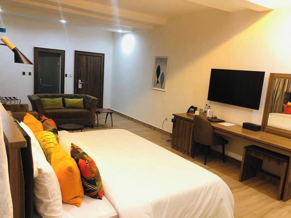 A hotel room with a bed, a desk, a chair, a television, and two doors.