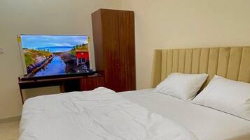 Ein Hotelzimmer mit einem Bett, einem Fernseher auf einem Schrank und einem Holzschrank.
