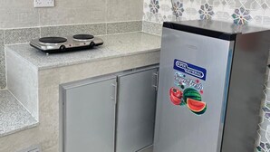 A kitchen with a stainless steel refrigerator, a gas stove, and a tiled backsplash. - SUNSET HOTEL (Al Amarat)