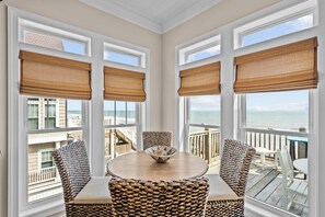 A sunroom with a view of the ocean, featuring a round table with chairs and a woven basket. - Fantasea #183 - 7 BD Oceanfront Home, Pet-Friendly w/ Hot tub! (North Topsail Beach)