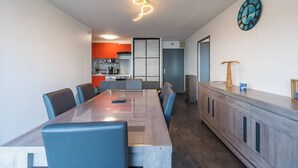 Un comedor moderno con una mesa larga, sillas azules y un armario de madera.