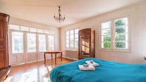 Una habitación con una cama, un armario de madera, una mesa y una araña.