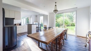 Una cocina amplia con una gran mesa de madera, armarios empotrados y vistas al exterior.