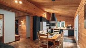 Interior de una cabaña de madera con comedor, cocina y una acogedora sala de estar.