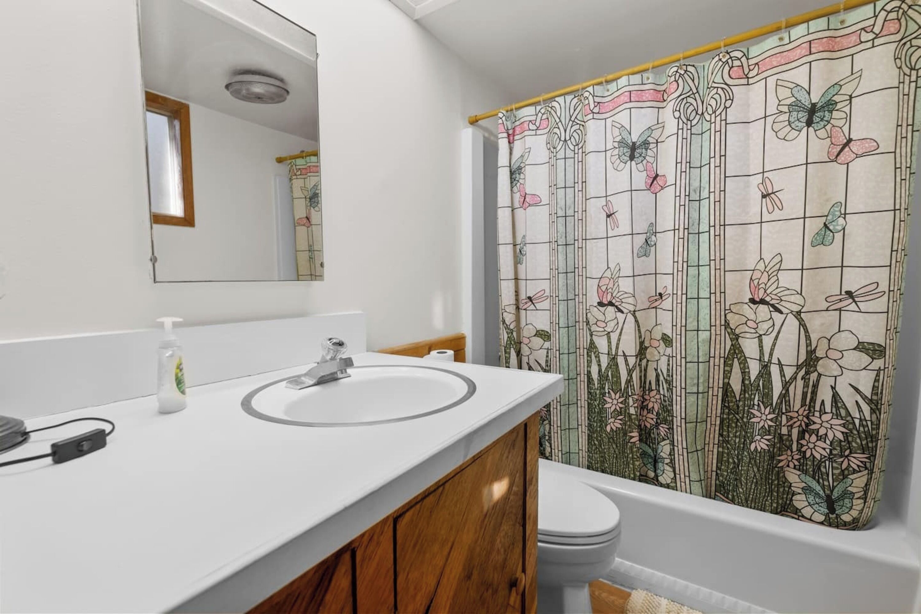 A bathroom with a white sink, wooden vanity, and a toilet.