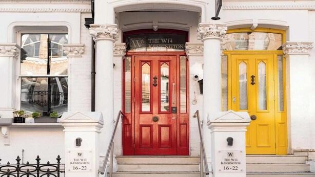 Une rangée de trois portes, chacune portant l’adresse suivante : « The W14 Kensington 16-22 ».