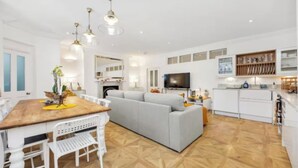 Un salon moderne comprenant un canapé, une table à manger et des chaises. On y trouve également une télévision, un coin cuisine et une cheminée.