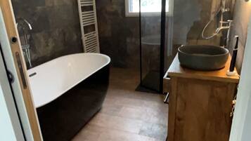A modern bathroom with a freestanding bathtub, a wooden vanity, and a large mirror.