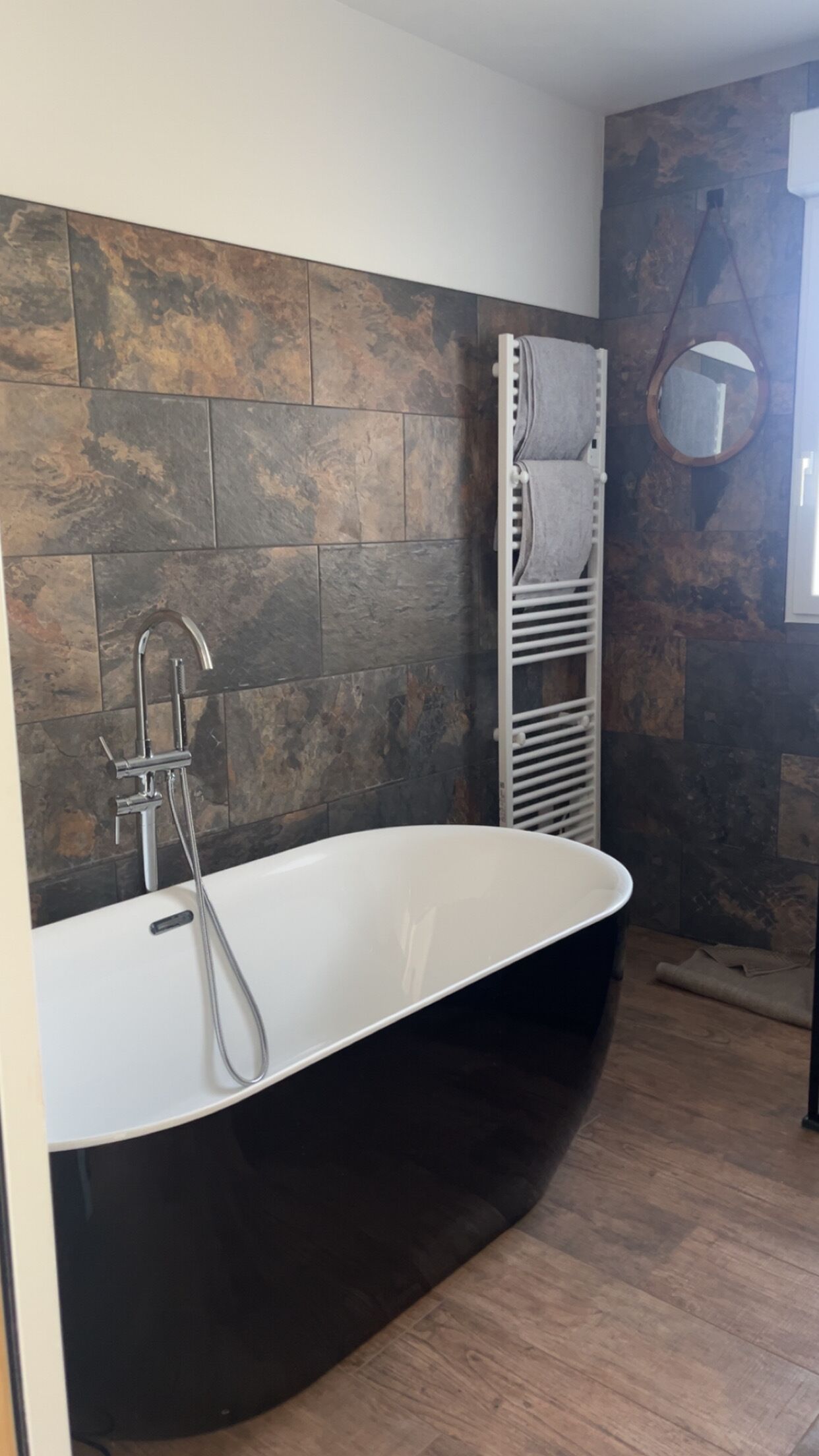 Une salle de bain moderne avec une baignoire sur pieds, un porte-serviettes mural et un miroir.