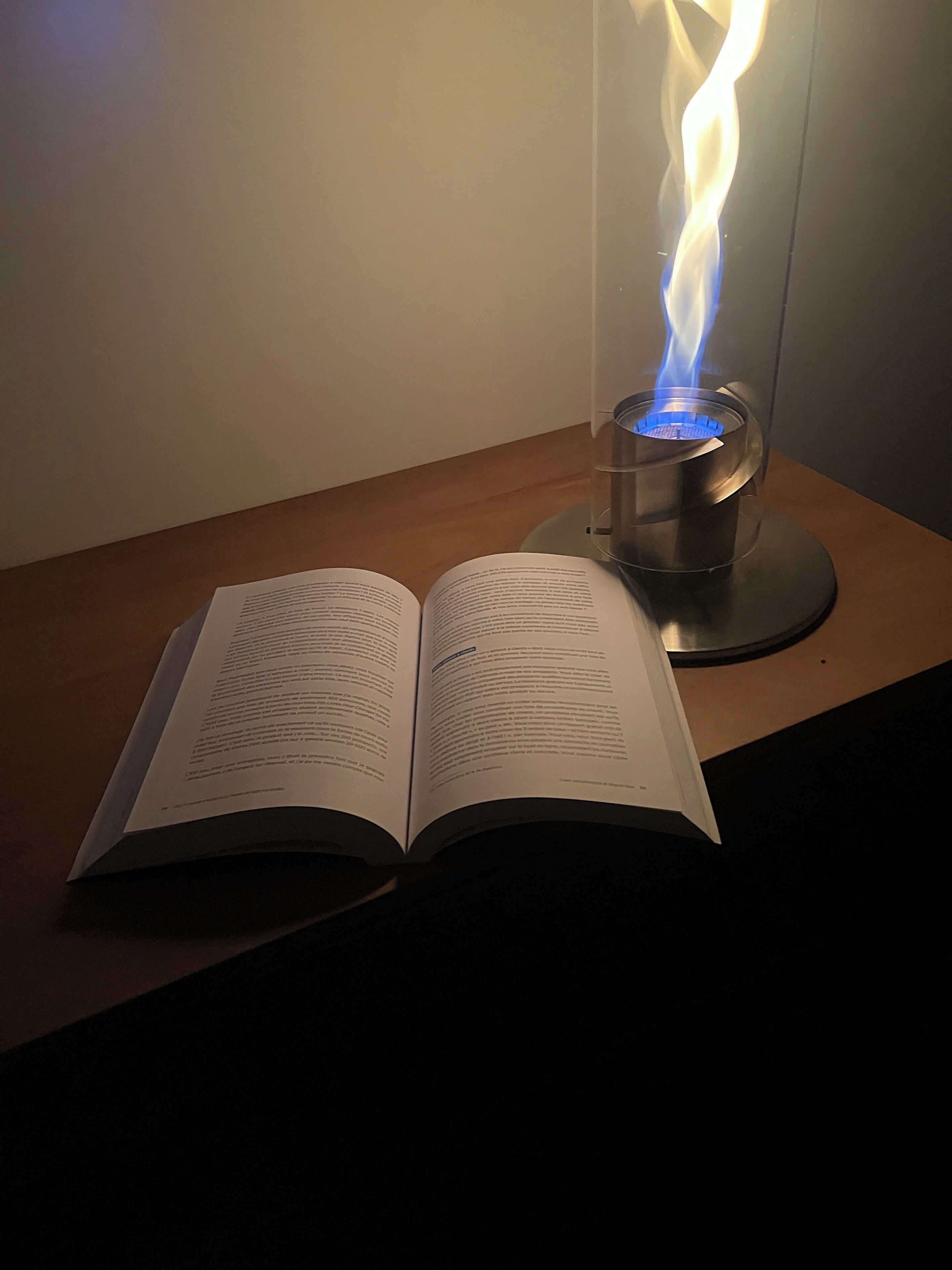 An open book on a wooden surface with a gas stove emitting blue flames.