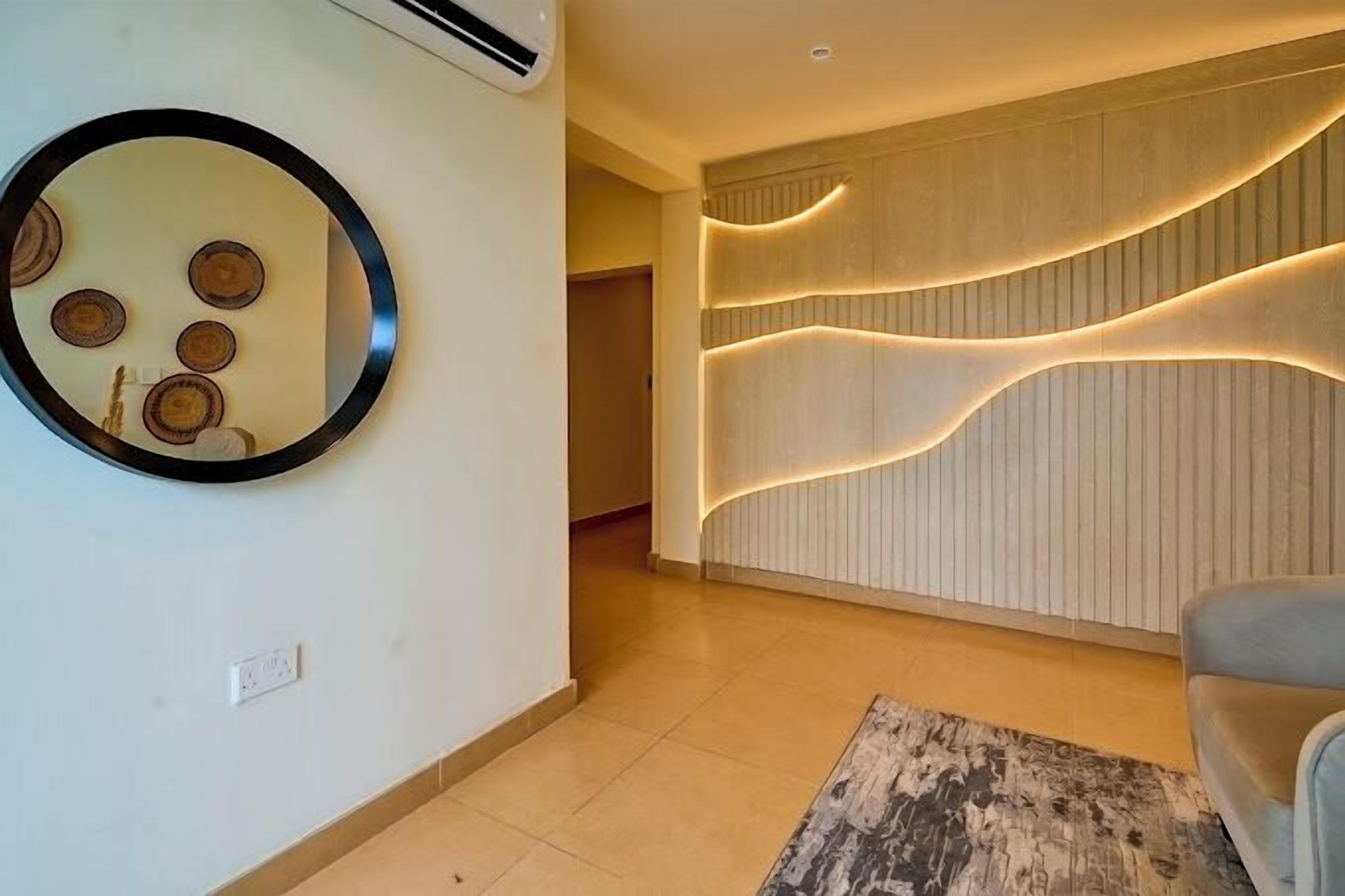 A modern interior with a round mirror, wooden wall paneling, and a light-colored rug.