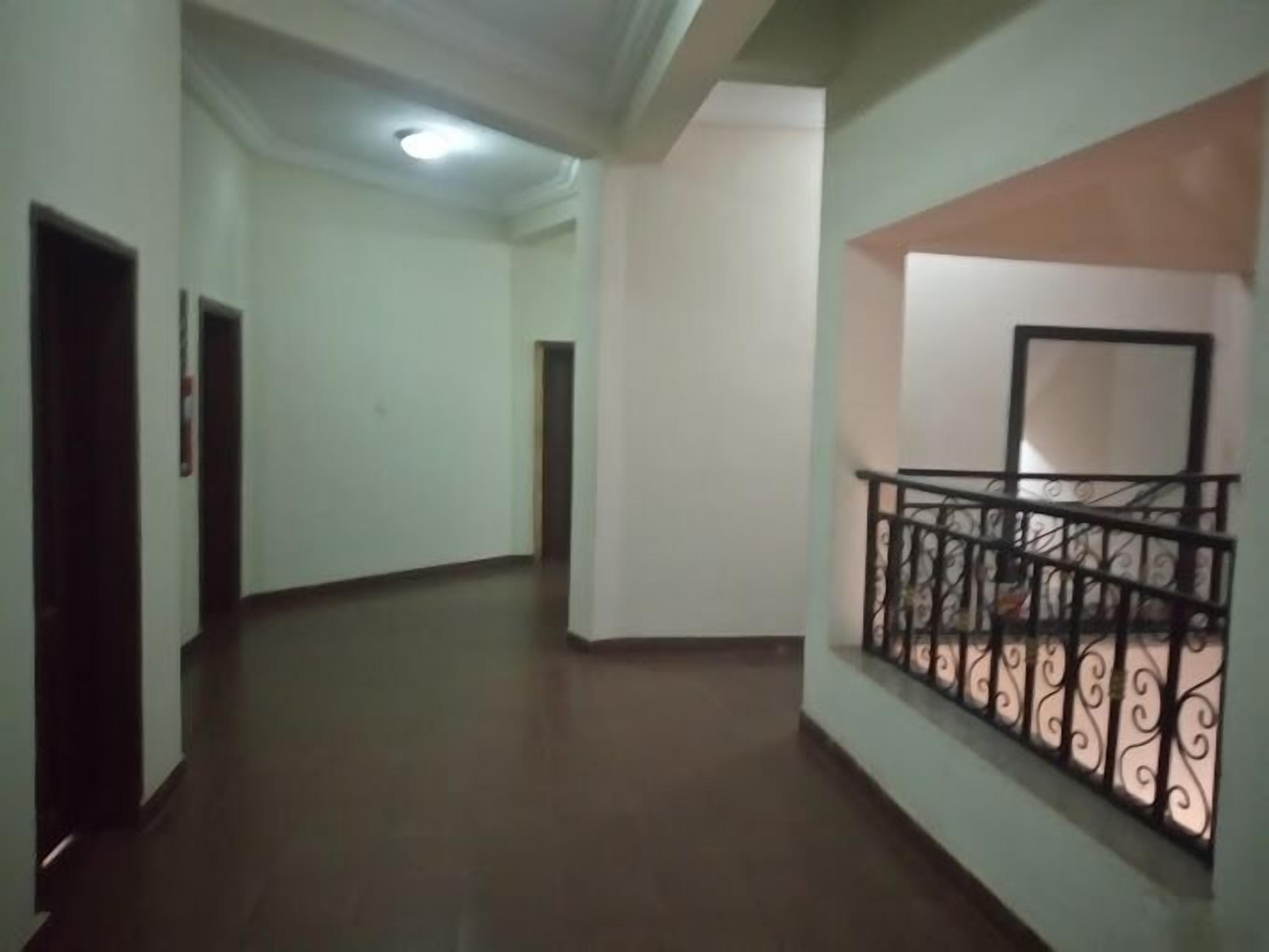A corridor with a staircase on the right, featuring a metal railing.