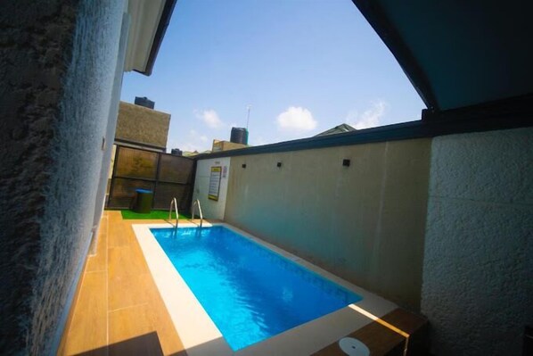 A small indoor swimming pool with a clear view of the sky and surrounding buildings. - Chexfield Suites and Apartments (Abuja)