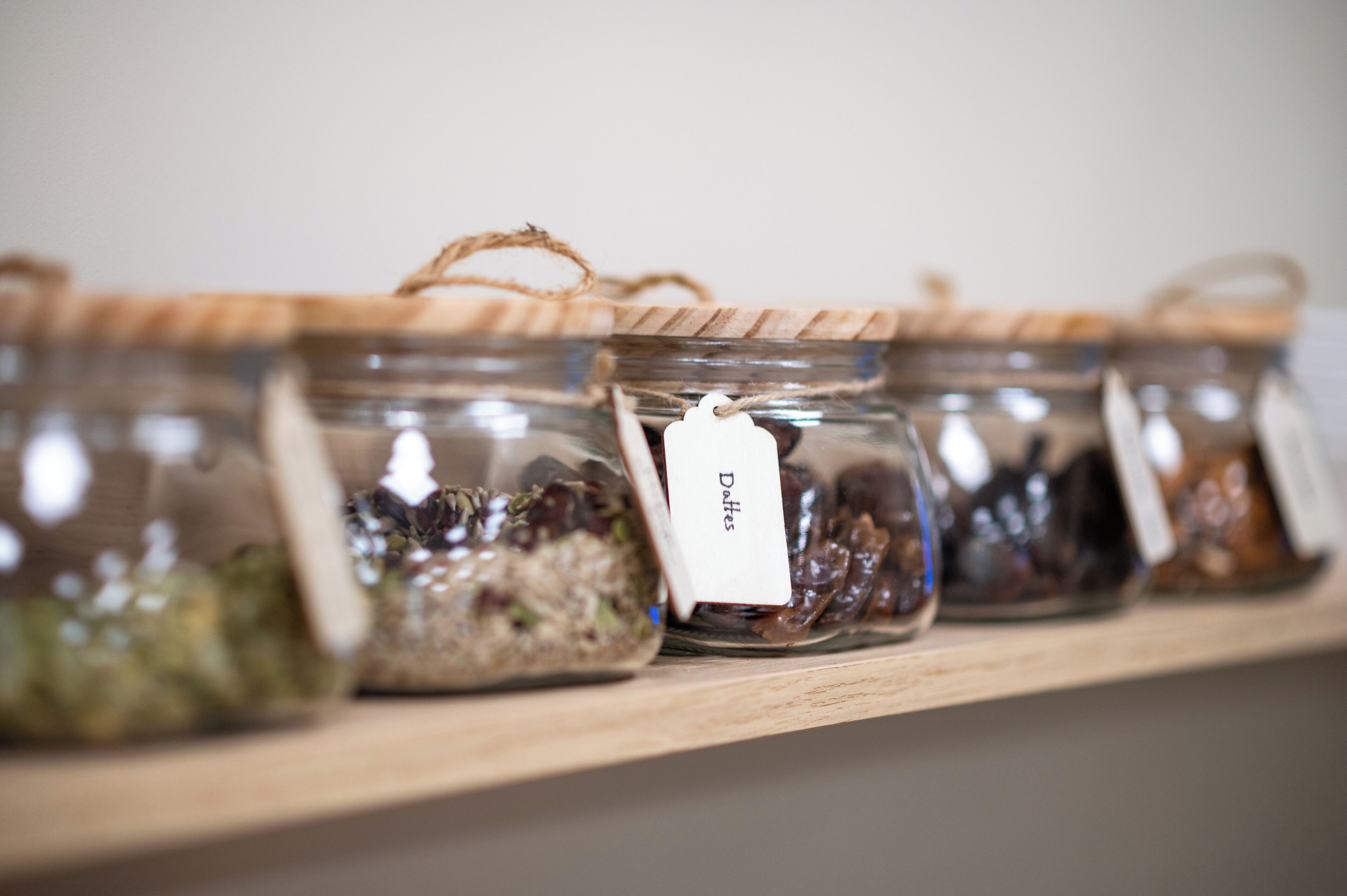 A shelf with glass jars containing various dried herbs and spices, each labeled with a tag.