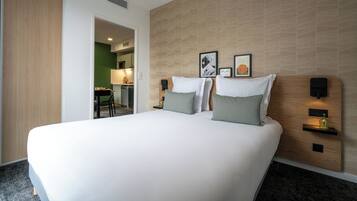 Ein modernes Hotelzimmer mit einem großen Bett, zwei Nachttischen mit Lampen, einem hölzernen Kopfteil und einer grünen Wand.