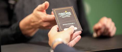 A person holding a card with "NEMEA" and "BIENVENUE" on it.