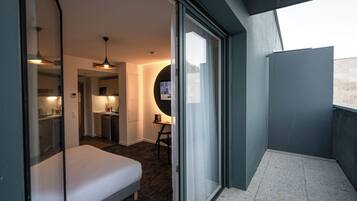 A compact hotel room with a bed, kitchenette, and a small dining area.
