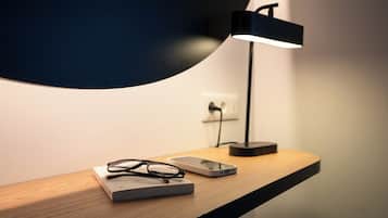 A desk with a laptop, glasses, and a smartphone.